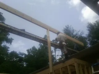 Carpenter setting a ridge beam over a new addition frame — Ice Dam Removal by Roofing Brothers in Glenelg