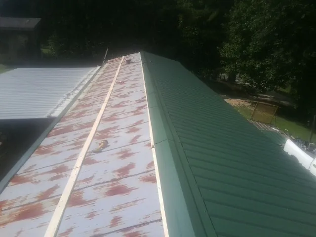 Old rusted panels beside newly installed green metal roofing — Wind Damage Roof Repair by Roofing Brothers in Glenelg