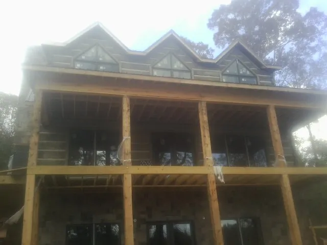 Dormers and porch framing on a large log home under construction — Roof Coating work by our crew in Glenelg