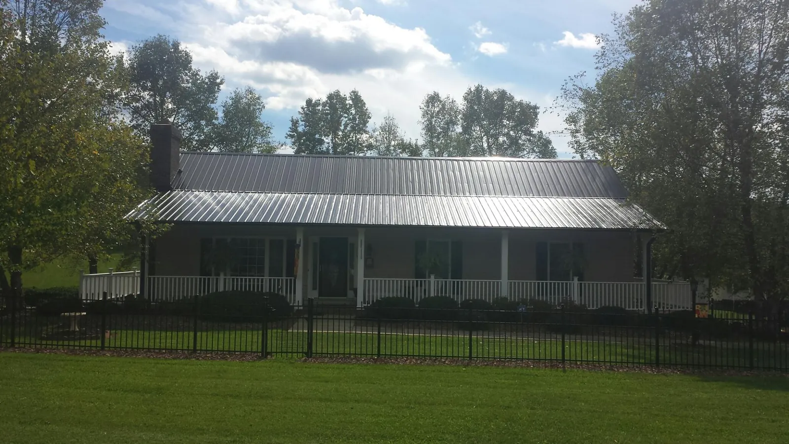 Gray metal roof on a brick ranch with a full width front porch — Gutter Guard Installation work by our crew in Glenelg
