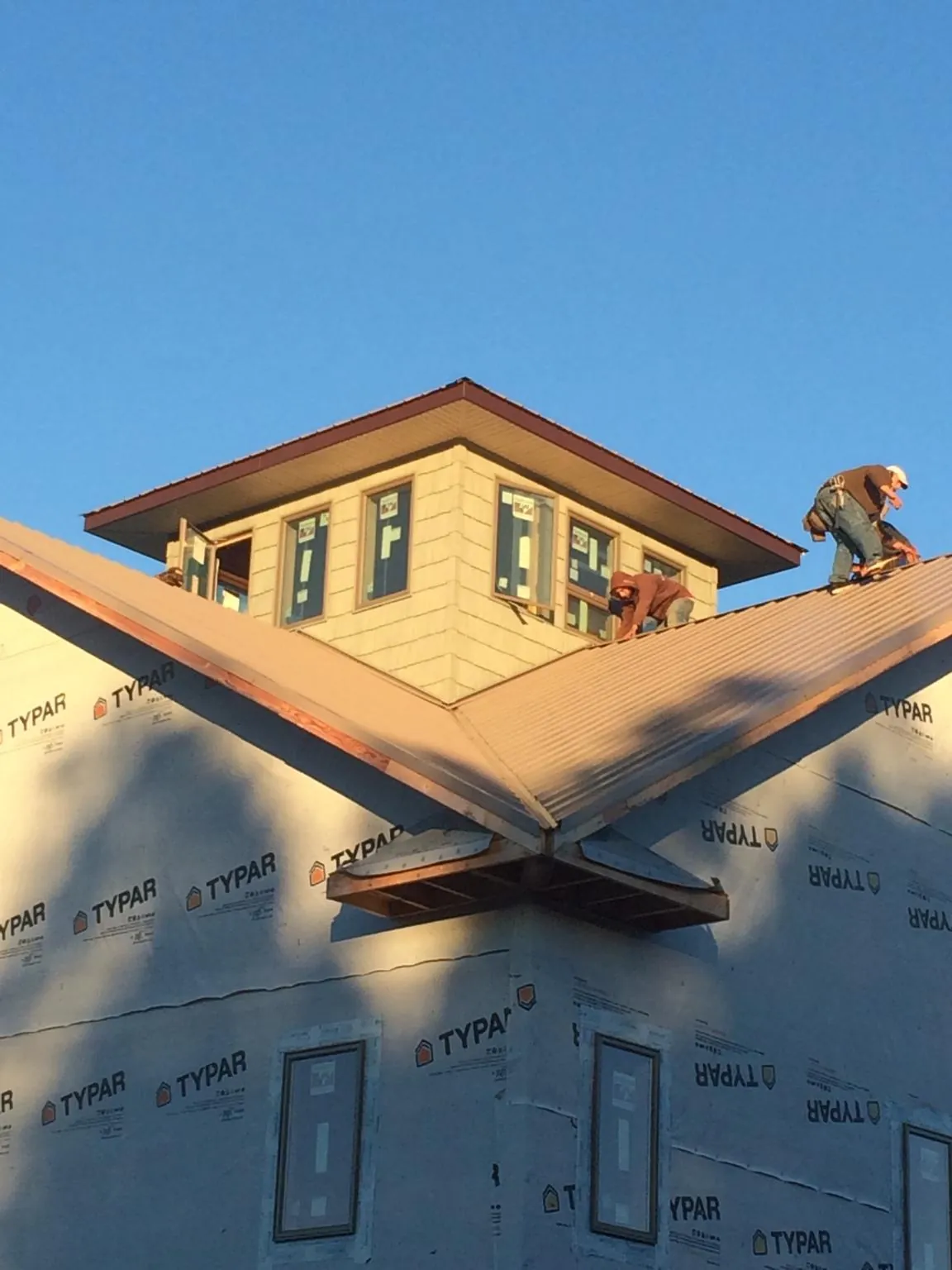 Roofers working around a rooftop cupola on a new metal roof at sunset — Roof Waterproofing in Glenelg by Roofing Brothers